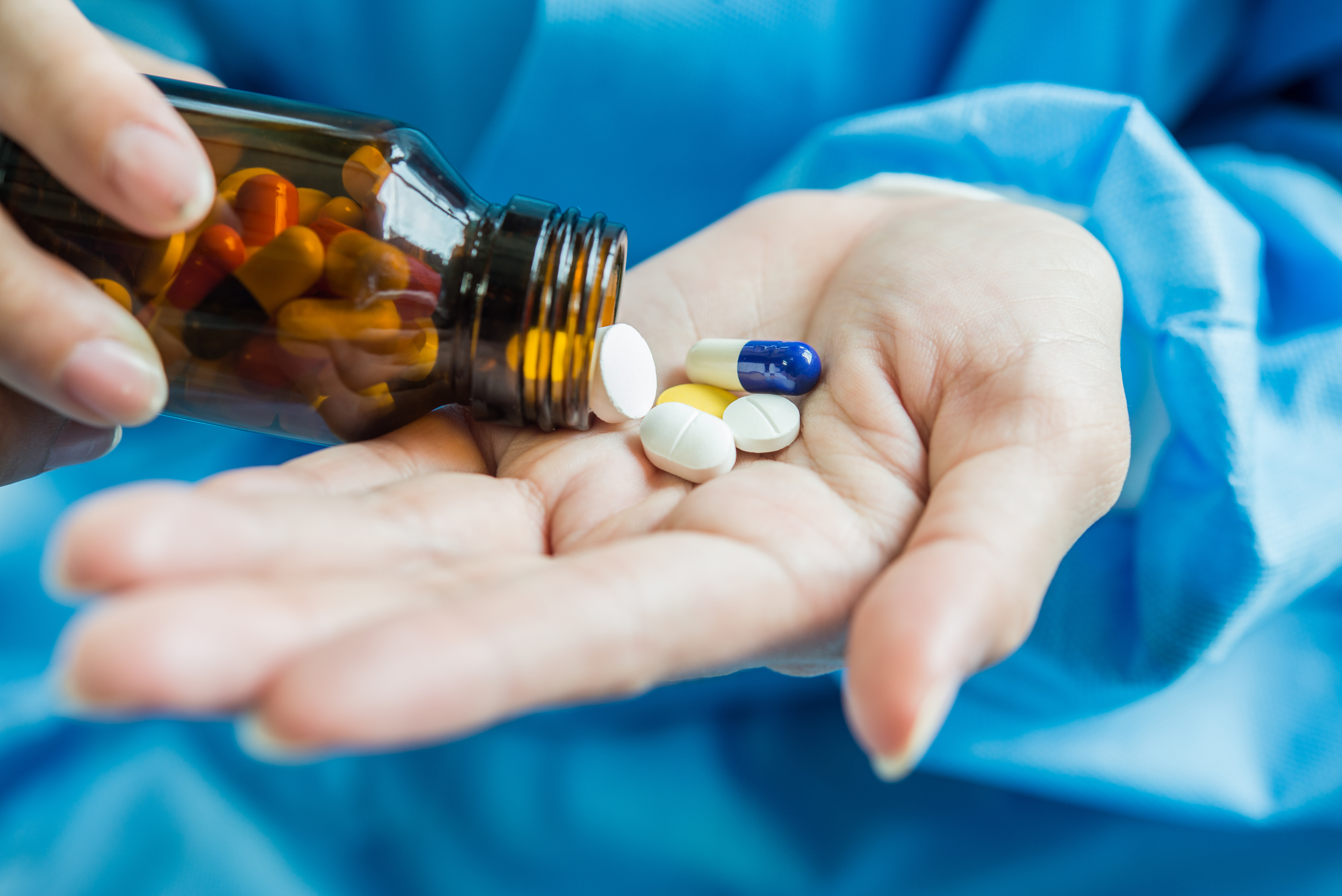 woman s hand pours medicine pills out bottle