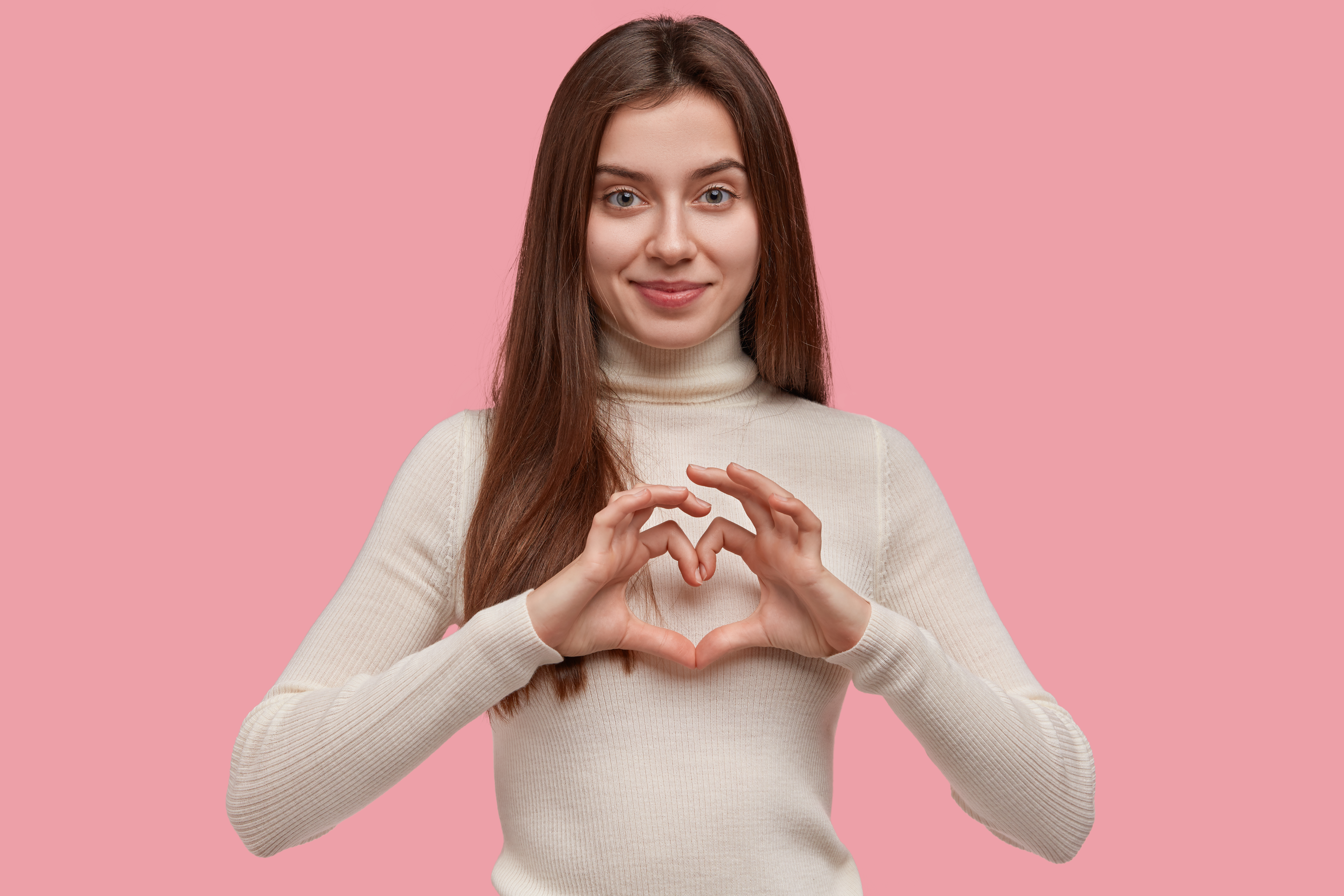 isolated shot friendly looking young girl shows heart gesture chest being love with somebody shows sympathy care